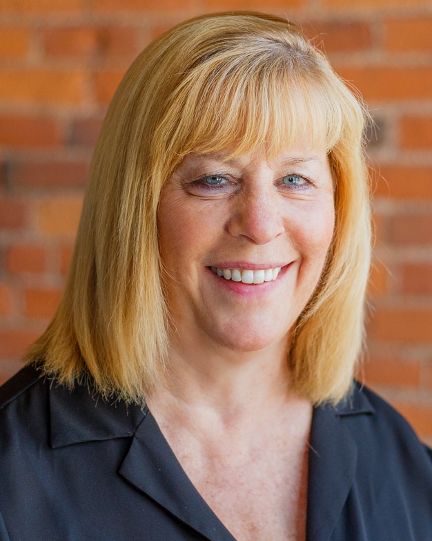 Barb Gambrell portrait headshot at Bradley Company offices in Fort Wayne with brick wall background