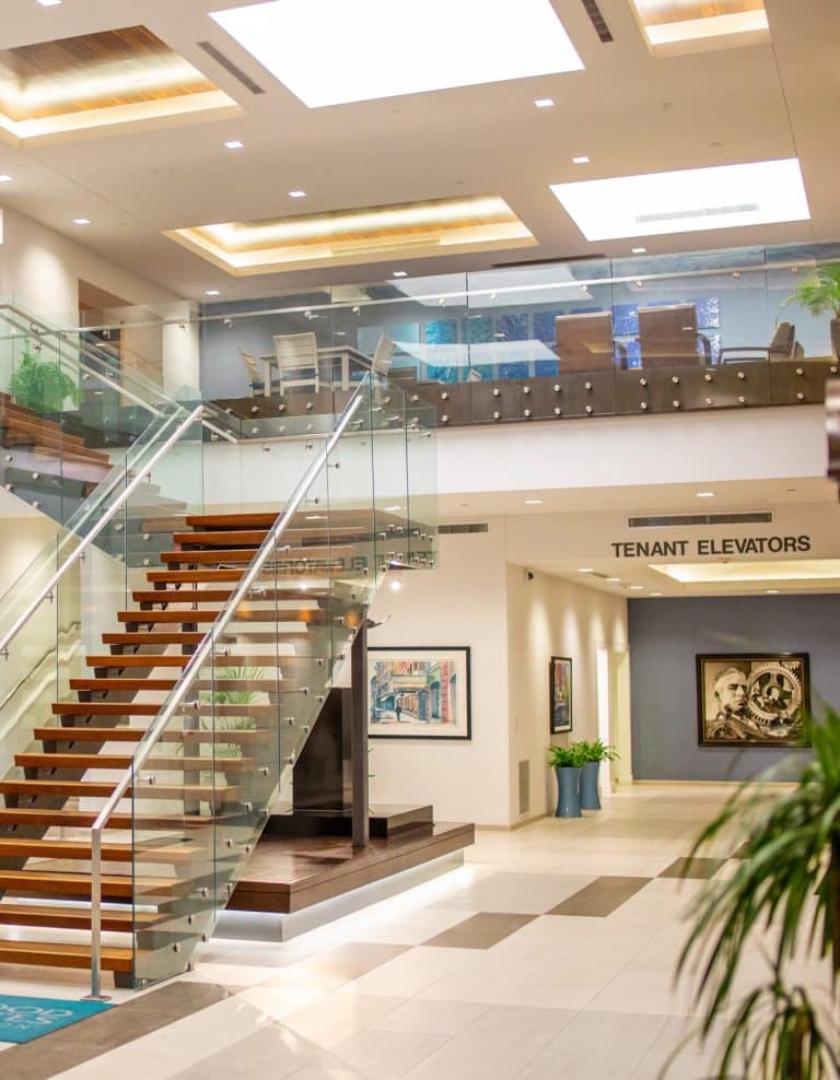 High resolution photo of modern office building interior featuring a glass and wood staircase, skylights, and a mezzanine conference area near the tenant elevators, conveying a professional and contemporary design.